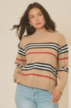 Woman wearing a beige sweater with horizontal stripes, standing against a neutral background.